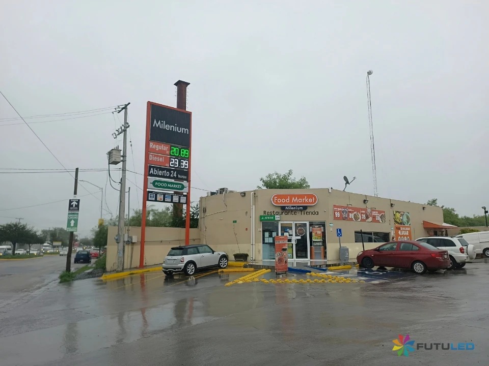 Letrero LED de precios de combustible fabricado por Futuled en una gasolinera Milenium, mostrando los precios de gasolina Regular y Diesel en un día lluvioso.