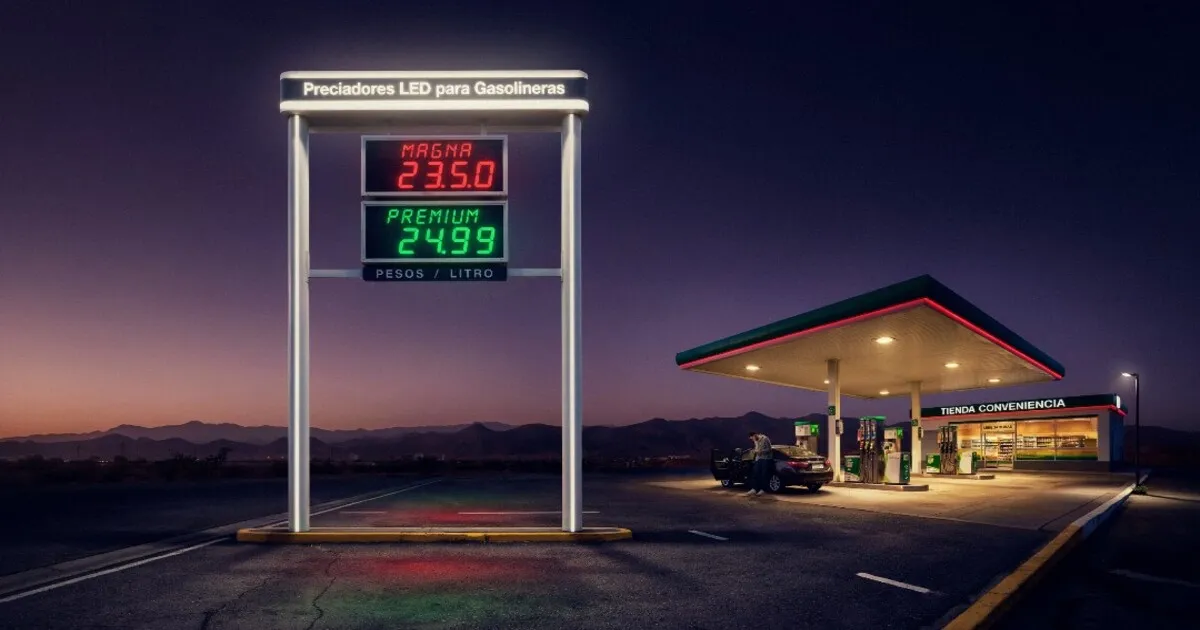 Tótem moderno con preciadores LED brillantes en una gasolinera al atardecer.